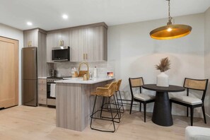 Une cuisine moderne dotée d’un îlot central, de tabourets de bar et d’une table à manger avec des chaises.