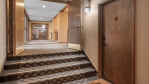 Un pasillo de hotel con escaleras alfombradas que llevan a una puerta con el número 15.