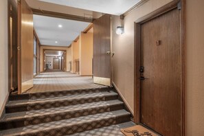 Un couloir d’hôtel avec un escalier recouvert de moquette menant à une porte portant le numéro 15.