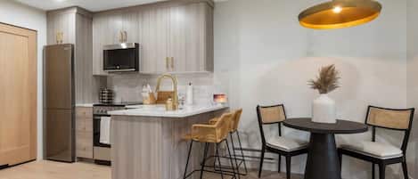 A modern kitchen with a central island, bar stools, and a round dining table with chairs.