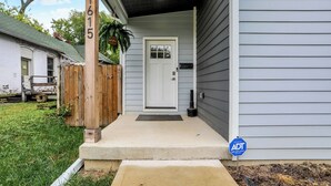 Une maison avec un porche à l’avant, une clôture en bois et une boîte aux lettres.