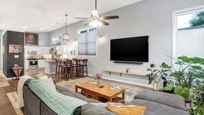 Un salon moderne avec un canapé gris, une table basse en bois et un téléviseur à écran plat fixé au mur.