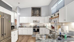 Une cuisine moderne avec des armoires blanches, des appareils en acier inoxydable et un comptoir en granit.