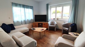 A living room with a sofa set, a coffee table, a TV, and a window with curtains. - House in Perros-Guirec with WiFi 550m from Trestraou Beach (Perros-Guirec)