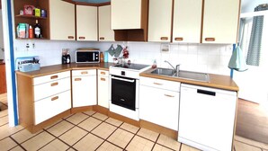 A compact kitchen with white cabinets, a microwave, a dishwasher, and a sink. - House in Perros-Guirec with WiFi 550m from Trestraou Beach (Perros-Guirec)