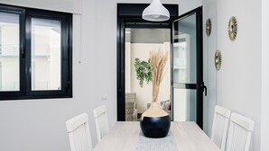 A dining area with a white table, black vase, and white chairs. - Elegant Apt. for 6 with Pool, Wifi and AC in Rota (Rota)