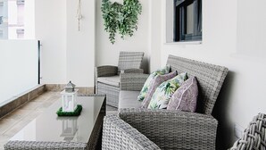 A modern living room with wicker furniture, a glass coffee table, and a decorative plant. - Elegant Apt. for 6 with Pool, Wifi and AC in Rota (Rota)
