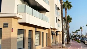 A modern building with a flat facade, large windows, and a brick base. - Elegant Apt. for 6 with Pool, Wifi and AC in Rota (Rota)