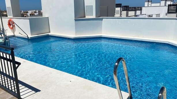 A rooftop swimming pool with clear blue water, surrounded by white walls and a metal railing. - Elegant Apt. for 6 with Pool, Wifi and AC in Rota (Rota)