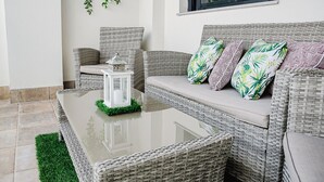 A wicker sofa with a glass-top coffee table and a small white lantern. - Elegant Apt. for 6 with Pool, Wifi and AC in Rota (Rota)