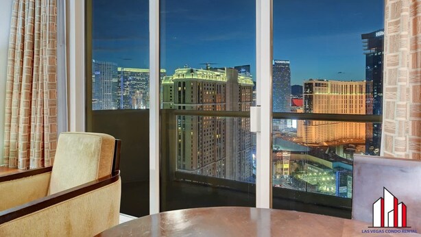 A hotel room with a large sliding glass door leading to a balcony with a city view. - MGM Signature-30-705 F1 Track & Strip View Balcony (Las Vegas)
