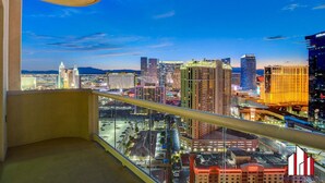 A high-rise hotel room with a cityscape view, including the Cosmopolitan hotel. - MGM Signature-30-705 F1 Track & Strip View Balcony (Las Vegas)