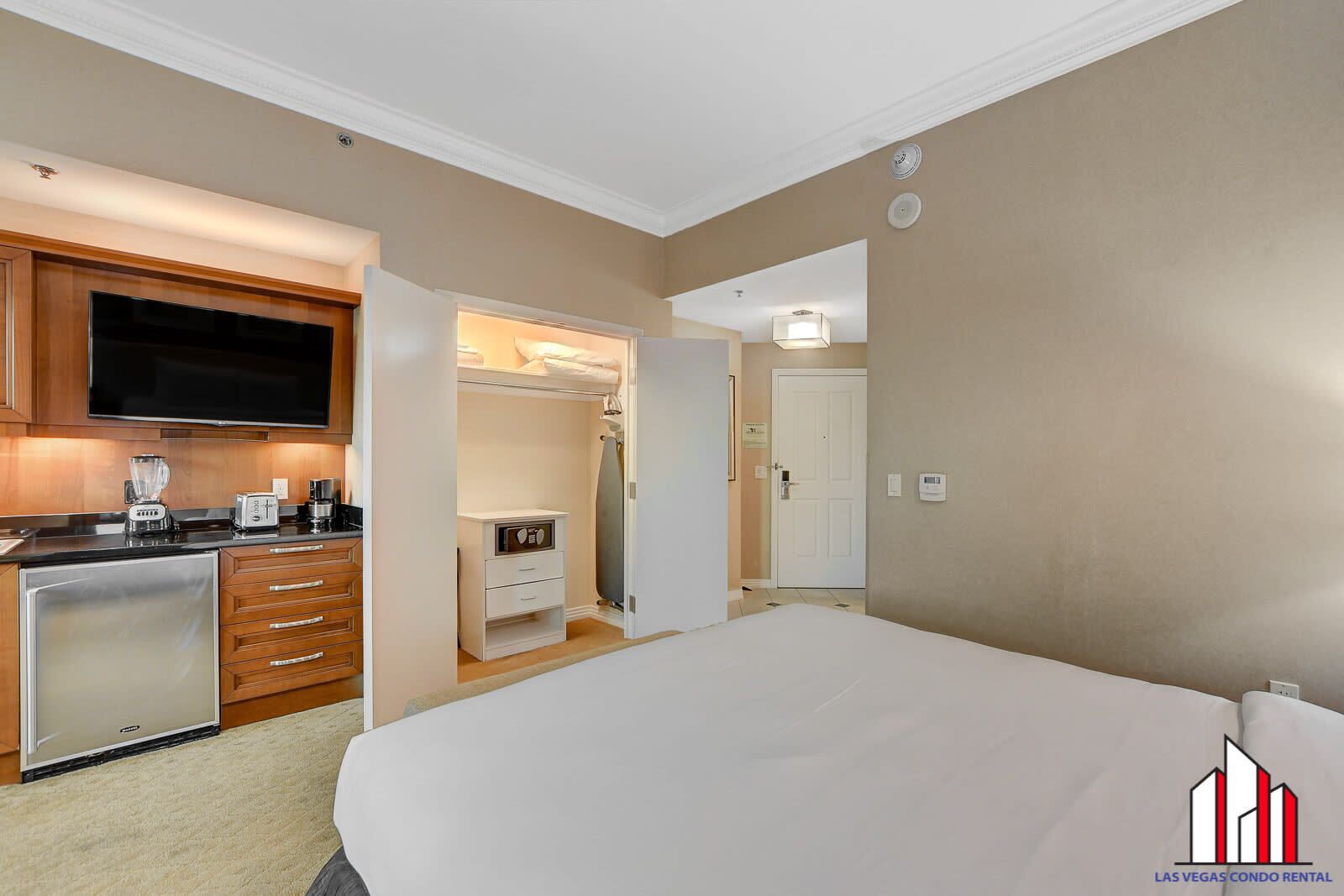 Una camera d'albergo con un letto, un angolo cottura con televisore, frigorifero e bagno piccolo.