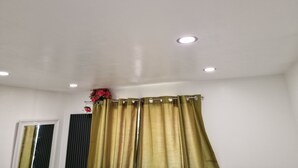 Une pièce aux murs blancs, dotée d’un plafond avec des spots encastrés et d’une fenêtre avec des stores verticaux.