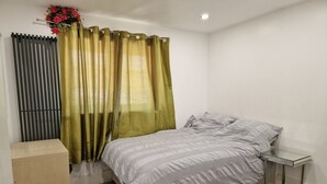 Une chambre à coucher avec un lit, une table de chevet, une armoire en bois et un radiateur.