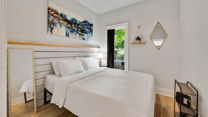 A bedroom with a bed, a ceiling fan, a painting, a window, and a mirror. - Teresa's Cottage - Walkable to downtown Sturgeon Bay (Sturgeon Bay)