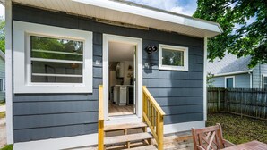 A small house with a wooden deck, a staircase leading to a door, and a view of the backyard. - Teresa's Cottage - Walkable to downtown Sturgeon Bay (Sturgeon Bay)