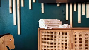 A room with a teal wall, wooden slats, a TV, a woven cabinet, and a wooden chair.
