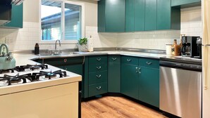 A kitchen with teal cabinets, a stainless steel refrigerator, and a gas stove.