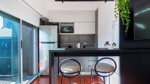 Una cocina moderna con microondas integrado, refrigerador y una barra con dos taburetes.