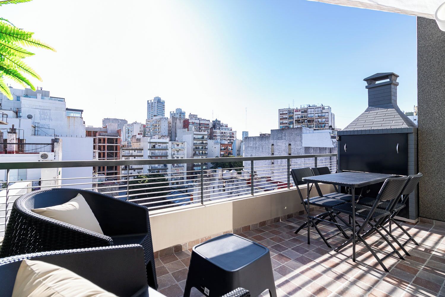 Eine Dachterrasse mit Blick auf die Stadt, einem Grill und Gartenmöbeln.