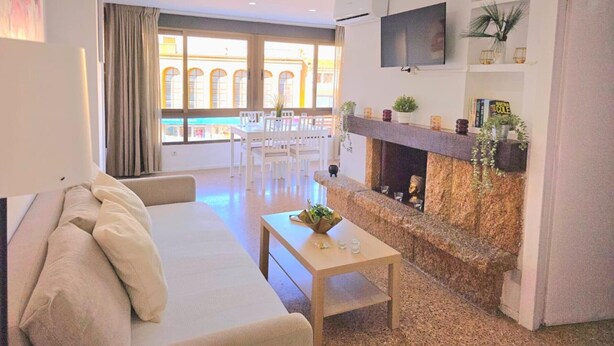 Una sala de estar moderna con chimenea, un sofá, un comedor y un televisor montado en la pared.