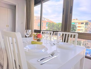 A dining table set with plates, cutlery, and wine glasses, with a fruit bowl and bananas on the table. - Luxury Getaway in Nogalera, Torremolinos with Parking (Torremolinos)