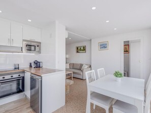 A compact kitchen with modern appliances, a dining area with a white table and chairs, and a living space with a sofa and artwork on the walls. - Luxury Getaway in Nogalera, Torremolinos with Parking (Torremolinos)