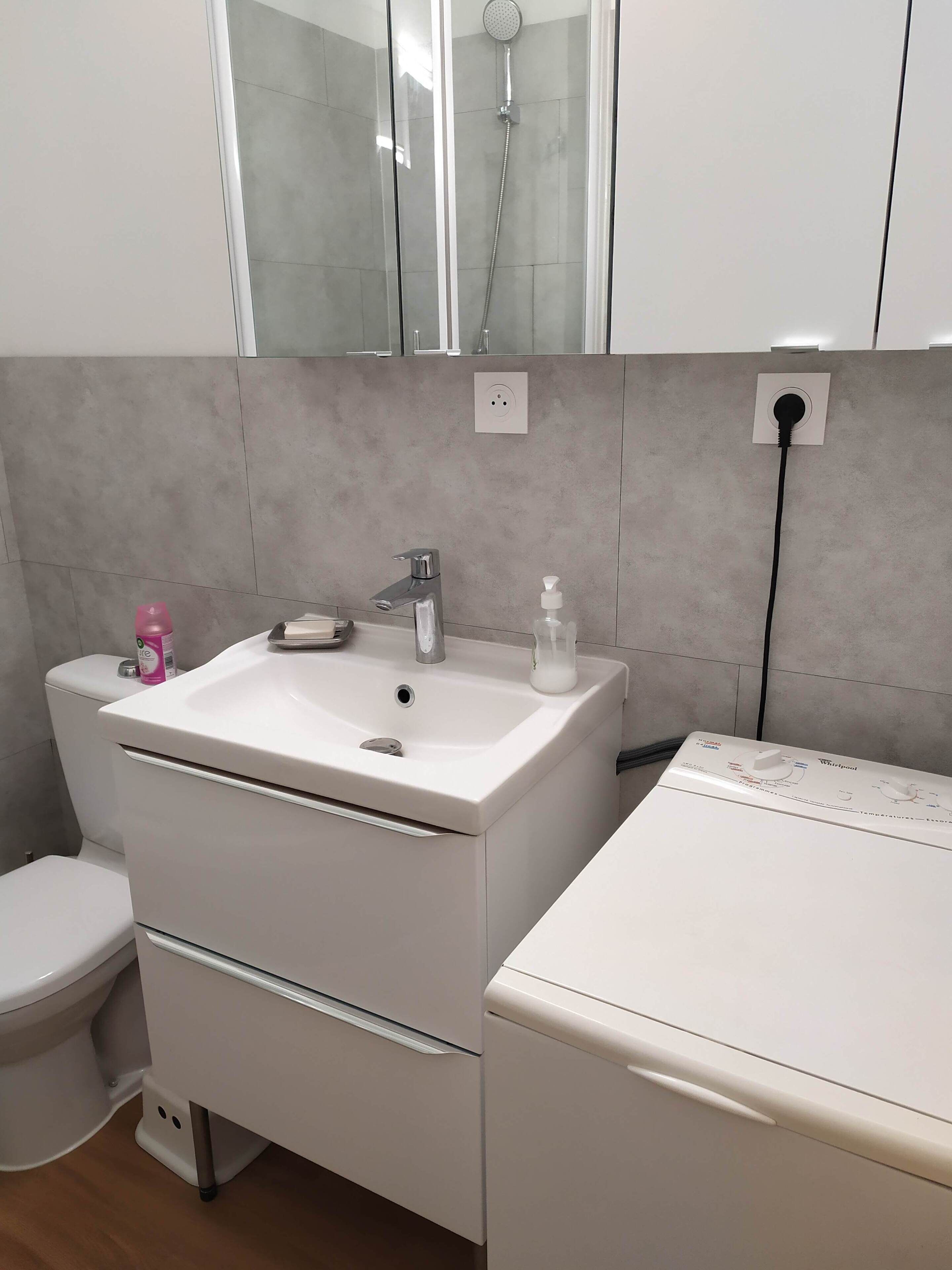 Een badkamer met een wit wastafel, toilet en douche.
