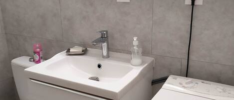 Een badkamer met een wit wastafel, toilet en douche.