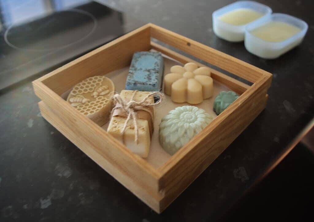 Una caja de madera con varios jabones de diferentes formas y diseños.