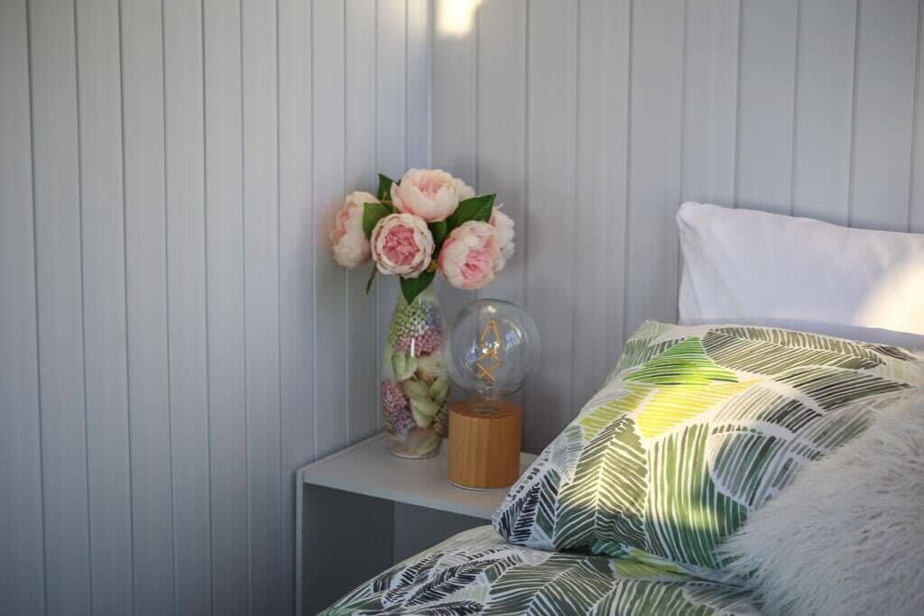 Une chambre à coucher avec un lit, une table de chevet, un vase de fleurs et un globe décoratif.