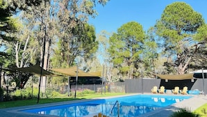 A swimming pool with lounge chairs and a shaded area, surrounded by trees. - Briggs' Bluff View at Grampians' Edge by Tiny Away (Dadswells Bridge)