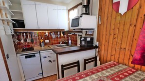 A compact kitchen with white cabinets, a microwave, a coffee maker, and a small refrigerator.