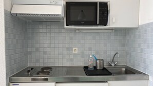 Ett kök med mikrovågsugn, spis, diskho och diskmaskin.