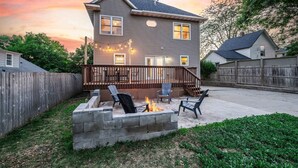A two-story house with a deck, outdoor seating, and a fire pit. - Grand Palace Cottage Escape (Sioux Falls)