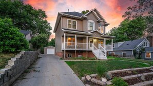A two-story house with a front porch, a covered driveway, and a well-maintained lawn. - Grand Palace Cottage Escape (Sioux Falls)