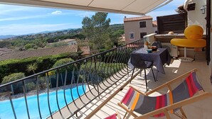 A balcony with a view of a swimming pool and surrounding landscape. - Fleurie by Interhome (Fréjus)