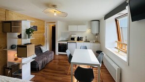 A compact living space with a kitchenette, a dining area, and a cozy seating area with a bed. - Charming studio with parking, mountain view, near Mont-Dore center (Mont-Dore)