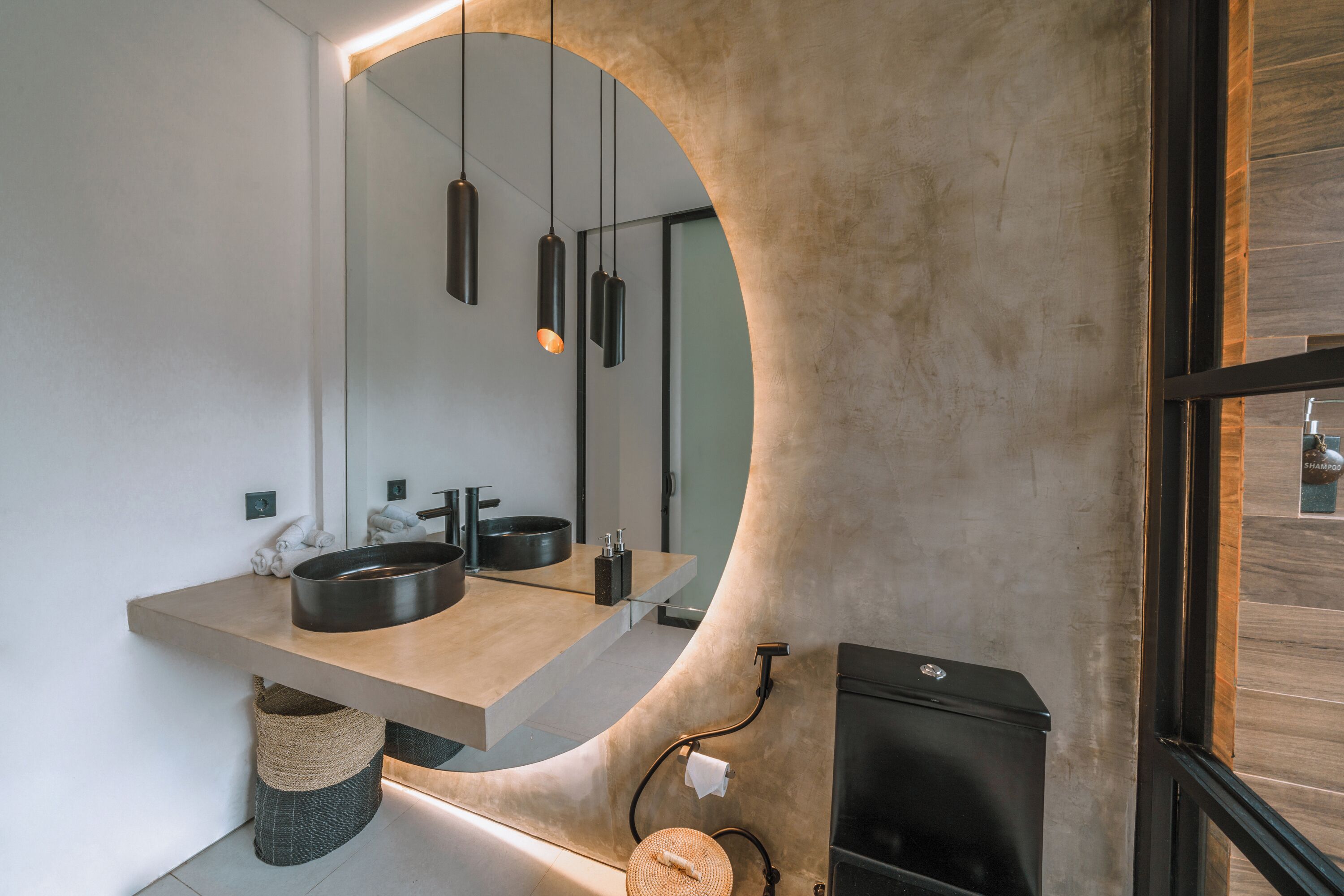 A modern bathroom with a large mirror, a wooden vanity, a black sink, and a black heater.