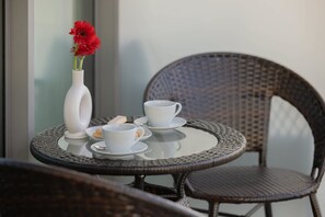 A round table with a white vase and red flowers, two white cups, and a plate with cookies. - Miedzyzdroje | Gryfa Pomorskiego 70 | Modern Apartment | Sea View (Miedzyzdroje)