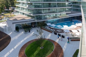 A modern hotel with a rooftop pool, outdoor seating, and a landscaped courtyard.