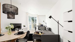 A modern, well-lit room with a dining area, a sofa, and a desk.