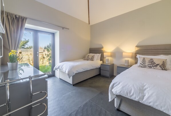Une chambre d’hôtel moderne équipée de deux lits, d’un bureau et d’une porte-fenêtre coulissante donnant sur l’extérieur.