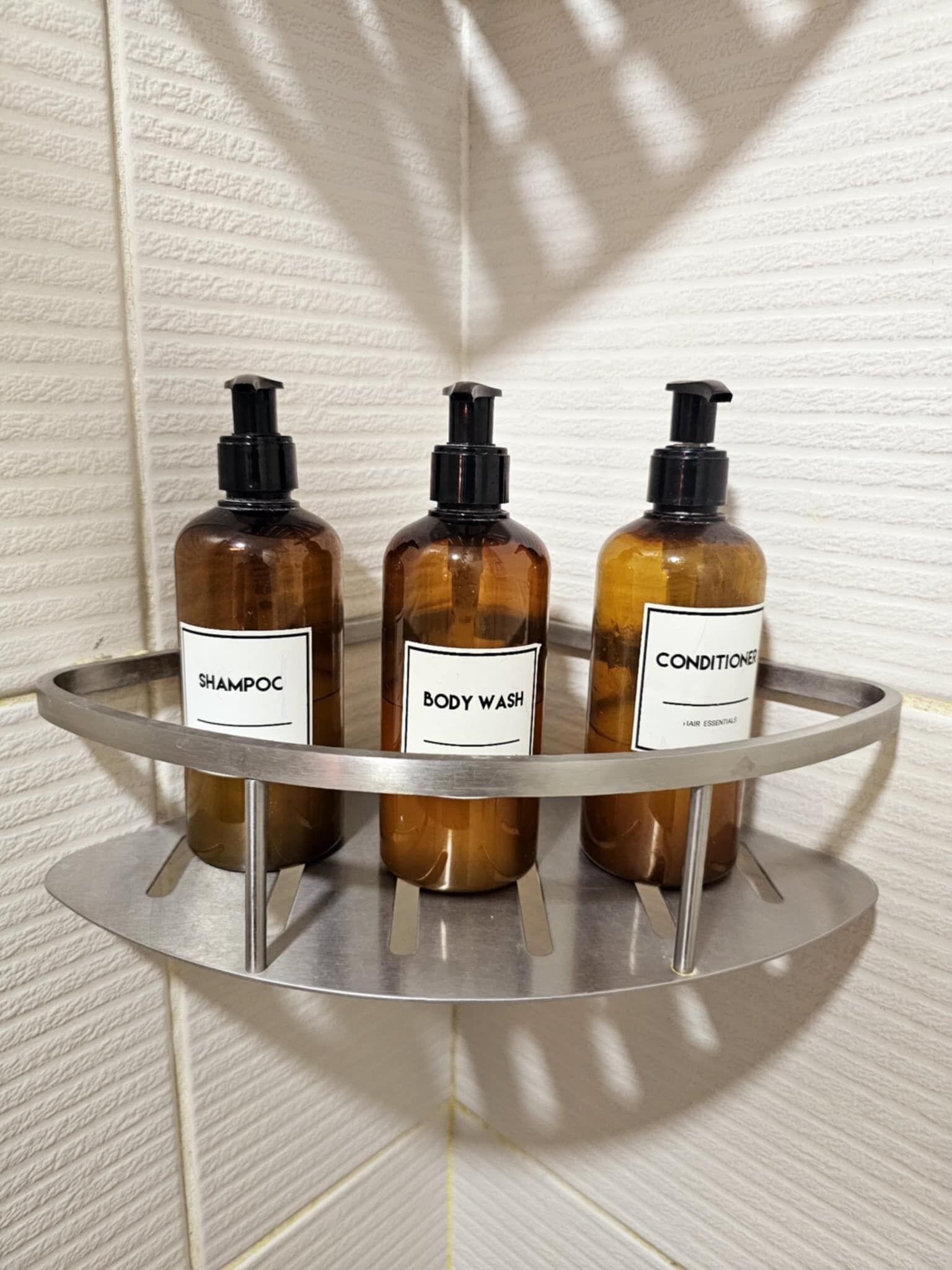 Trois bouteilles de produits d’hygiène personnelle sont posées sur une étagère en métal.