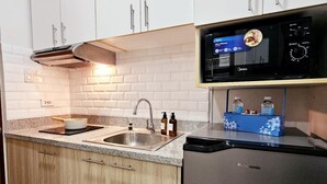 Una cocina moderna con armarios blancos, un refrigerador de acero inoxidable, un microondas y un fregadero.