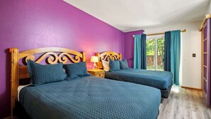 A room with two beds, purple walls, a wooden headboard, a nightstand, and a window with curtains. - Adventure Base • Hot Tub • Grill • Close to Town (Moab)