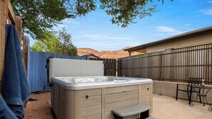 A hot tub with a wooden deck and a small table and chair nearby. - Adventure Base • Hot Tub • Grill • Close to Town (Moab)