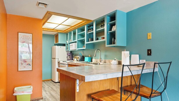 A compact kitchen with teal cabinets, a wooden island, and a small trash bin. - Adventure Base • Hot Tub • Grill • Close to Town (Moab)