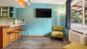 A modern kitchen with a bar area, a flat-screen TV mounted on the wall, and a window with a view of the street. - Adventure Base • Hot Tub • Grill • Close to Town (Moab)